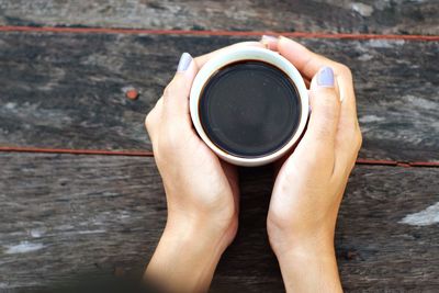 Cropped hands of woman having black coffee at table