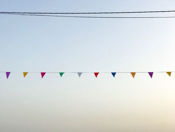 Low angle view of bunting flags against clear sky