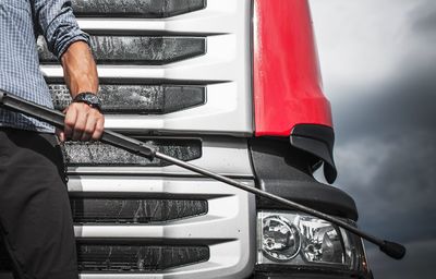 Midsection of man with metallic rod standing against bus