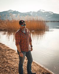 Young man wearing sunglasses standing by lake