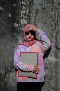 Portrait of woman standing against pink wall