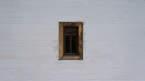 Closed small window on white brick wall of building