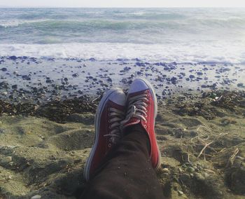 Low section of man on beach against sky