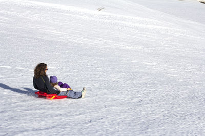 Little girl and her mom sledding in the snow