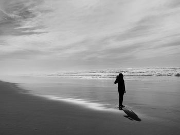 Full length of silhouette girl standing on beach against sky