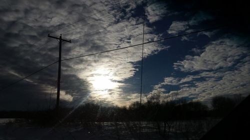 Low angle view of electricity pylon against sky during sunset