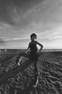 Side view of woman standing at beach against sky