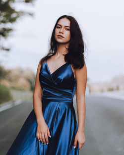 Young woman in blue dress standing on road