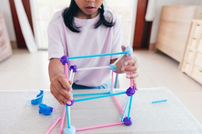 Cute asian child girl playing and creating with play dough and straws. 