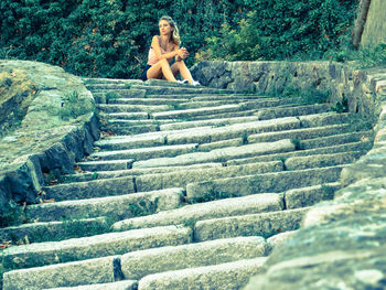 Low angle view of young woman sitting on steps