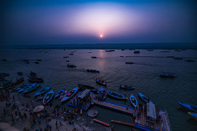 People at beach against sky during sunset