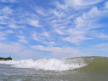 Waves splashing on sea against sky