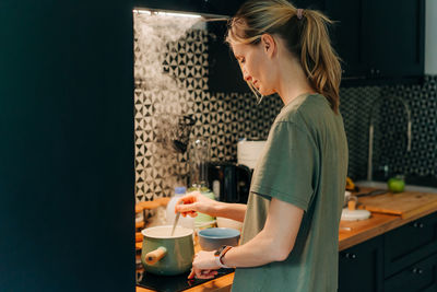 Young woman prepping and cooking in small city kitchen