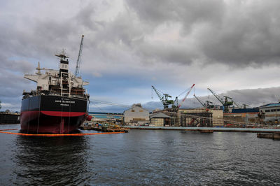 Cranes at commercial dock against sky