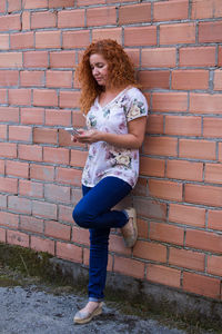 Full length of woman standing against brick wall