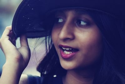 Close-up of young woman wearing hat looking away