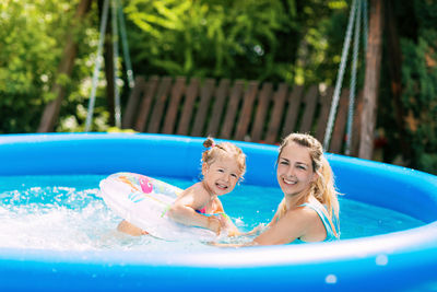Cheerful healthy mother and daughter play in swimsuits in the pool. time together, summer time