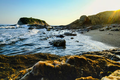 Rocks in sea against sky during sunset