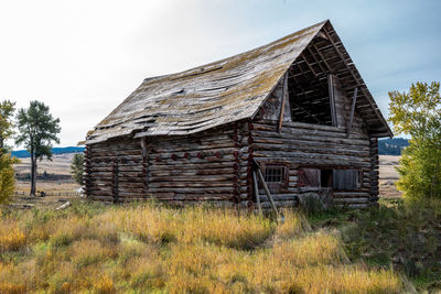 Old wooden house on field against sky