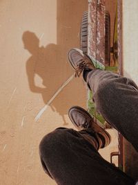 Low section of man with umbrella on shadow
