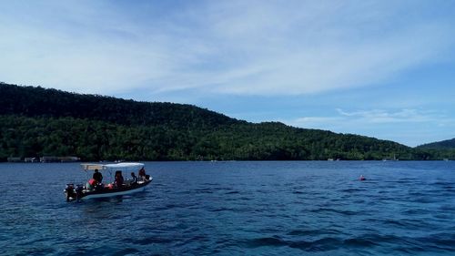 People on boat sailing in river against sky