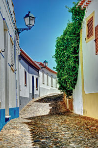 Street amidst houses against clear blue sky