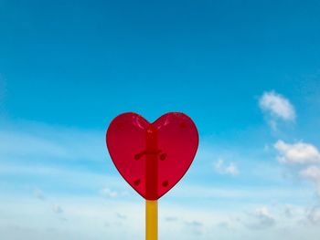 Close-up of red heart shape against blue sky