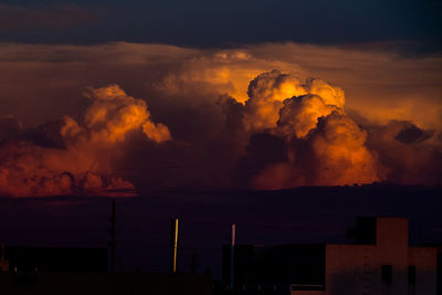 Silhouette factory against sky at sunset