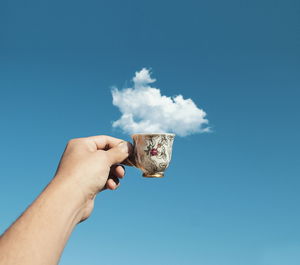 Low angle view of person holding umbrella against clear sky