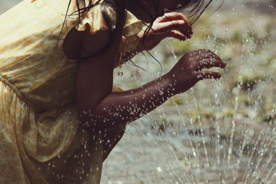 Midsection of girl by sprinkler on footpath