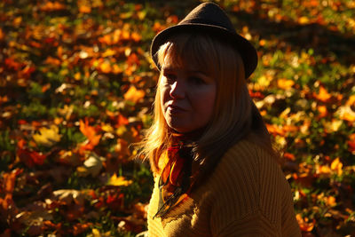 Closeup portrait of candid young caucasian blonde woman in colorful autumn park. bright dark stylish