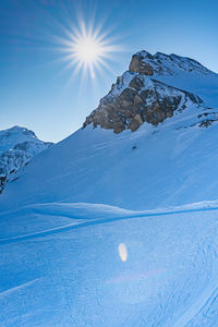 Scenic view of snowcapped mountains against bright sun