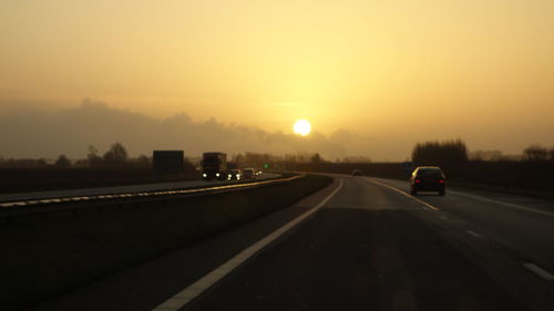 Cars on road against sky during sunset