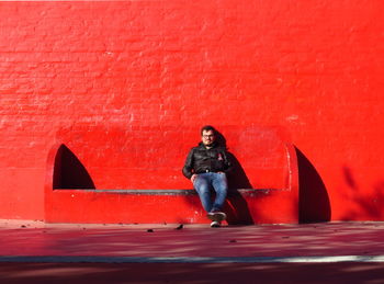 Man sitting against red wall