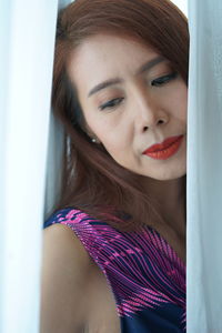 Beautiful woman looking down by curtain