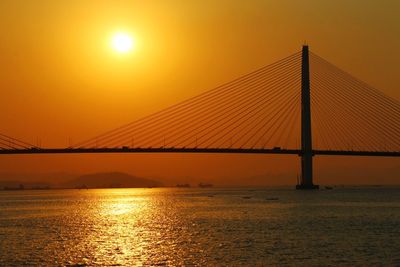 Suspension bridge over sea during sunset