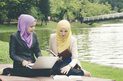 Businesswomen in hijab using laptop against lake