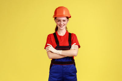 Portrait of engineer standing against yellow background