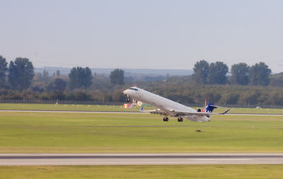 Airplane flying over grassy field against sky