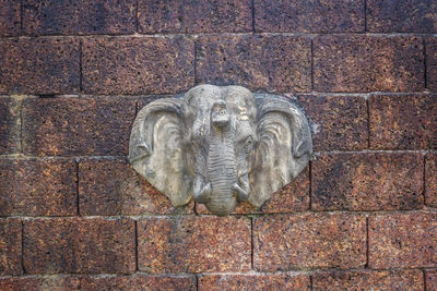 Close-up of statue against brick wall