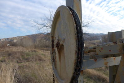 Close-up of rusty metal on field against sky