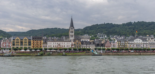 Buildings at waterfront against cloudy sky