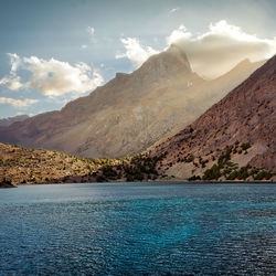 Scenic view of sea by mountains against sky