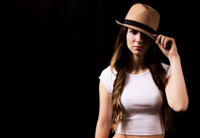 Portrait of young woman against black background