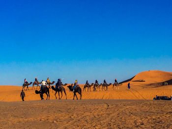 People riding horse in desert against sky