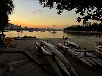 Boats moored in river at sunset