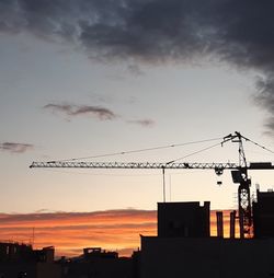 Low angle view of silhouette crane against sky during sunset