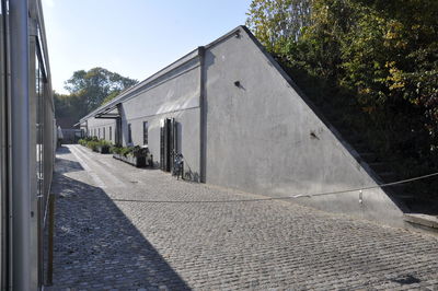 Road amidst buildings against sky on sunny day