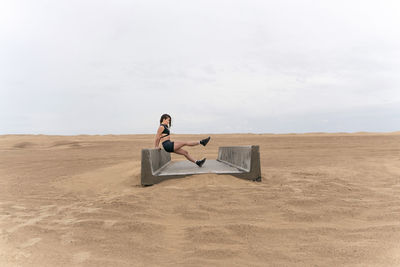 Woman exercising on concrete structure in desert