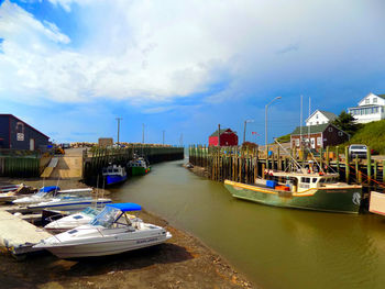 Boats moored at harbor in city against sky